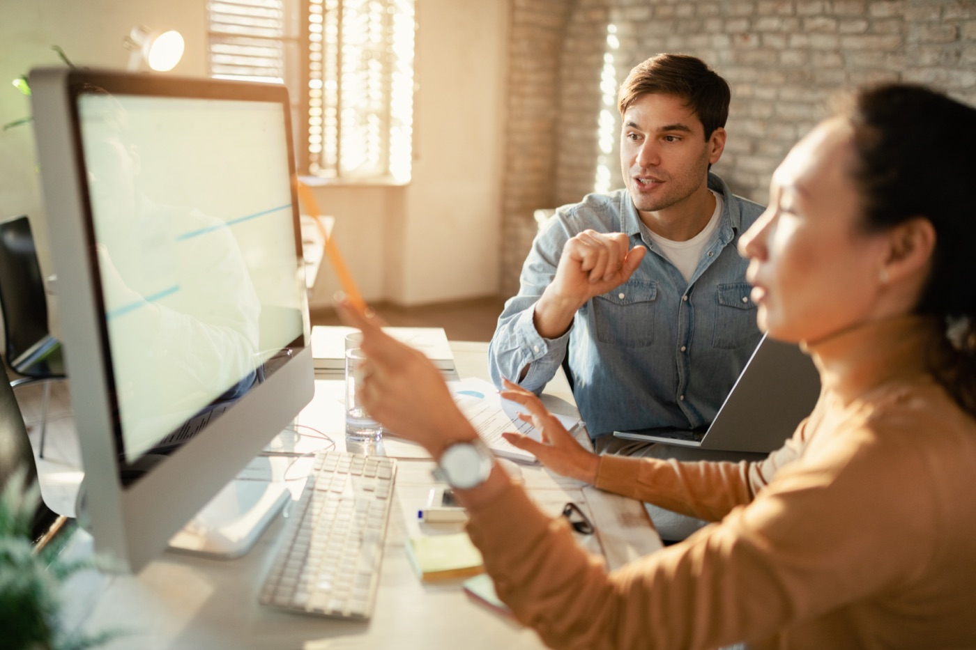 Two developers discussing AI agent evaluation results on a monitor