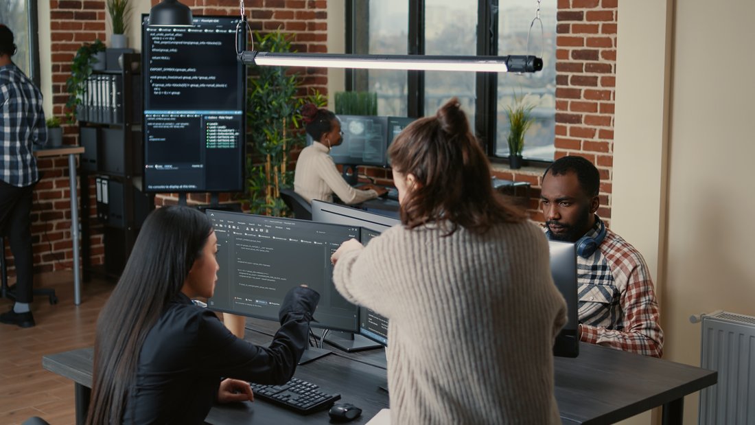 Developers reviewing code together on multiple monitors