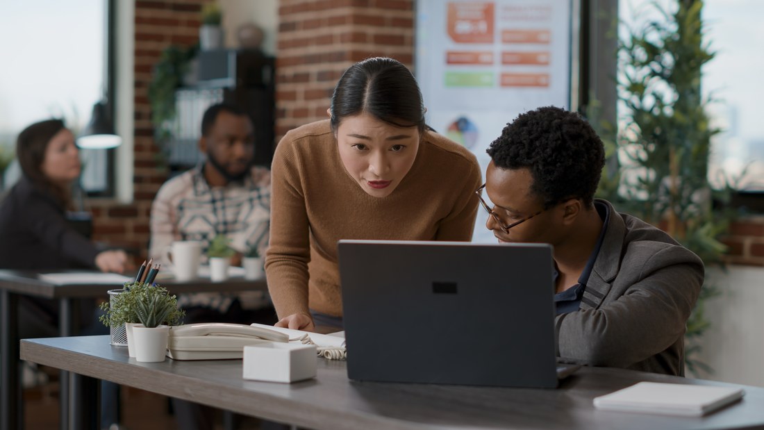 Two colleagues reviewing evaluation tool options together on a laptop