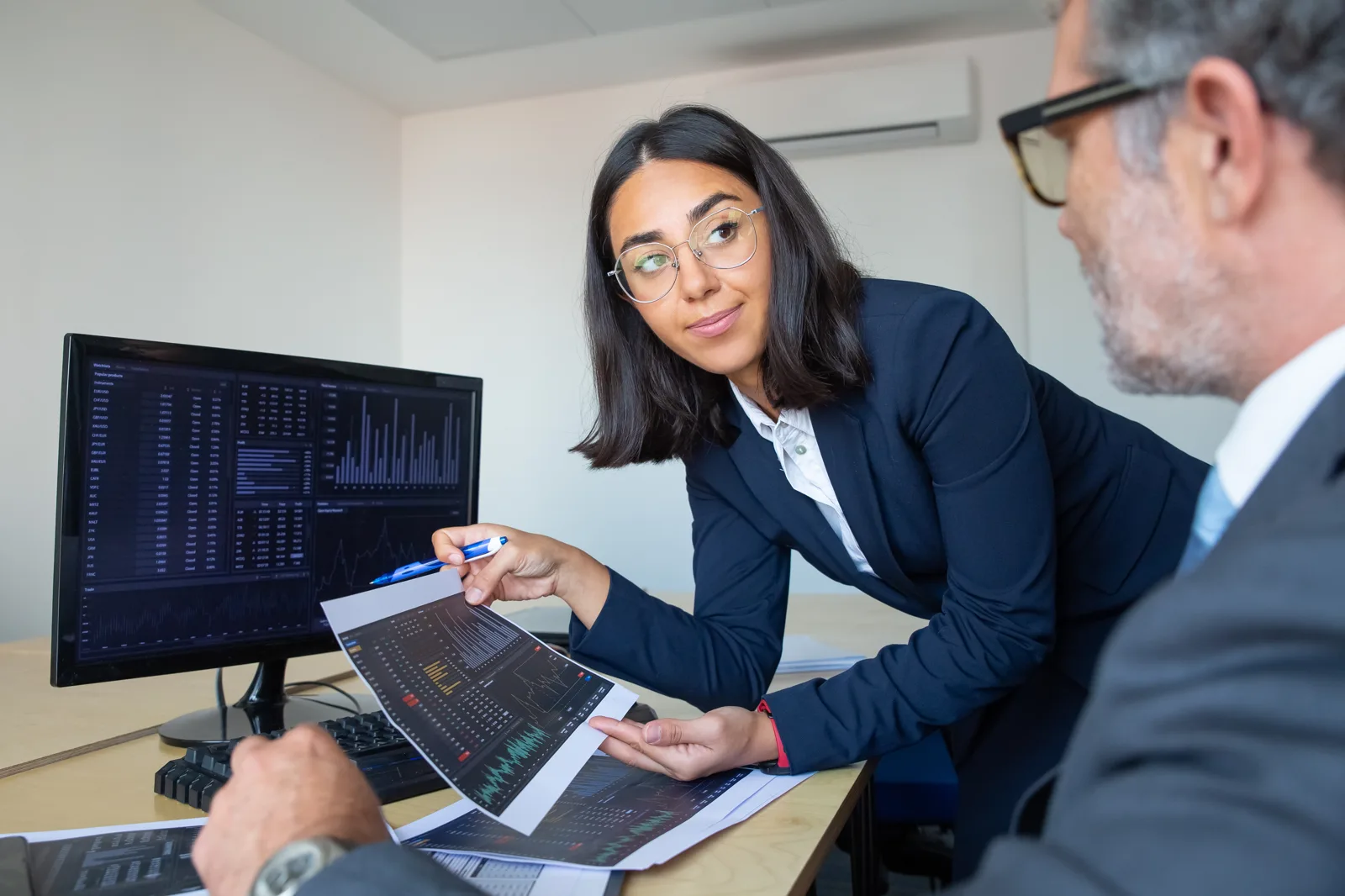 Banking analysts reviewing real-time financial data on a trading desk monitor