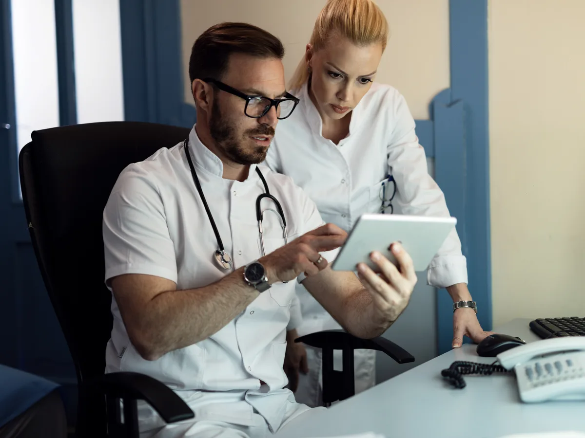 Doctor and nurse reviewing electronic health record data together in a clinical office