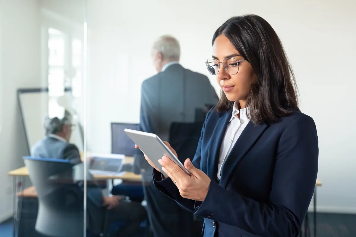 Insurance QA analyst reviewing claims processing data on a tablet in the office