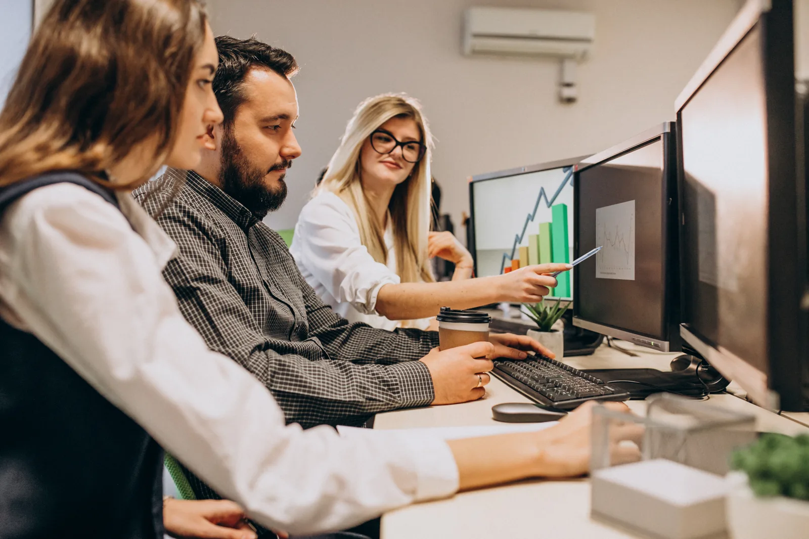 Software team reviewing a SaaS analytics dashboard on dual monitors in a modern office