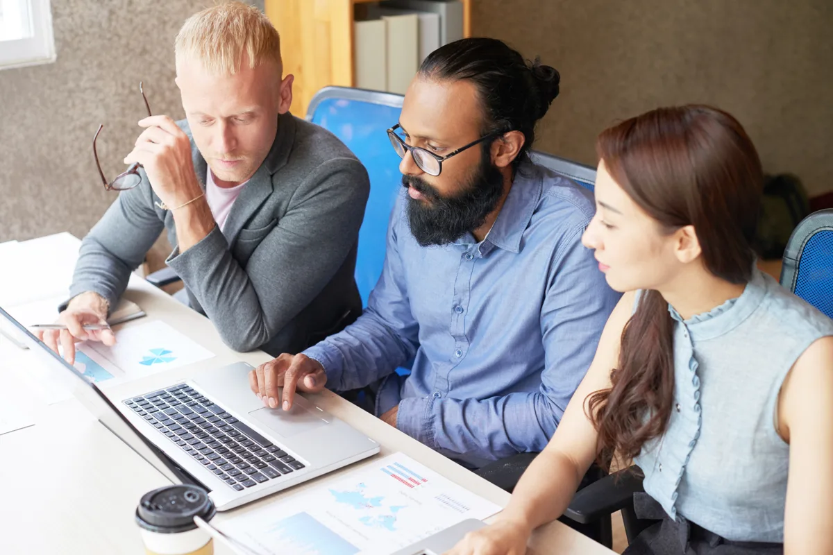 SaaS QA team reviewing multi-tenant test reports on a laptop with printed charts