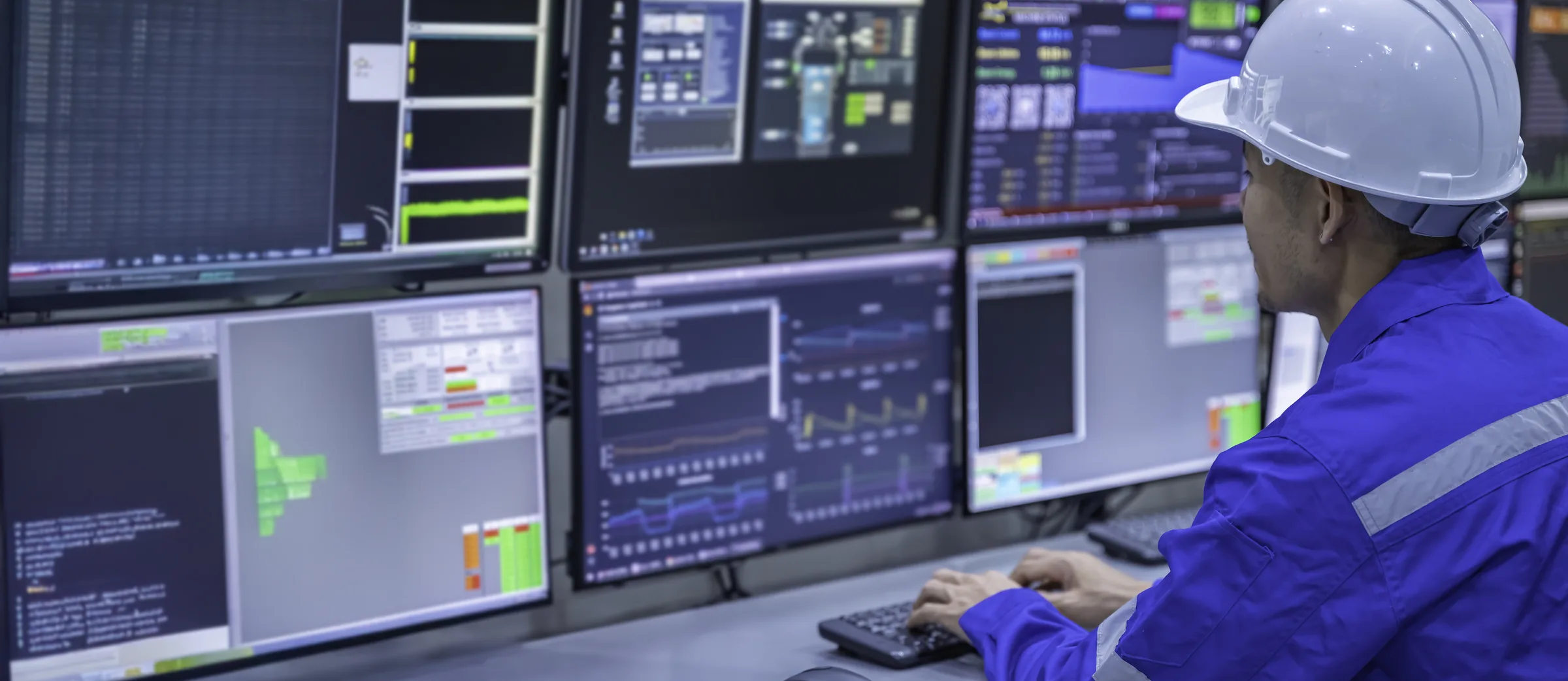 Telecom network operations engineer monitoring BSS and OSS dashboards on multiple screens